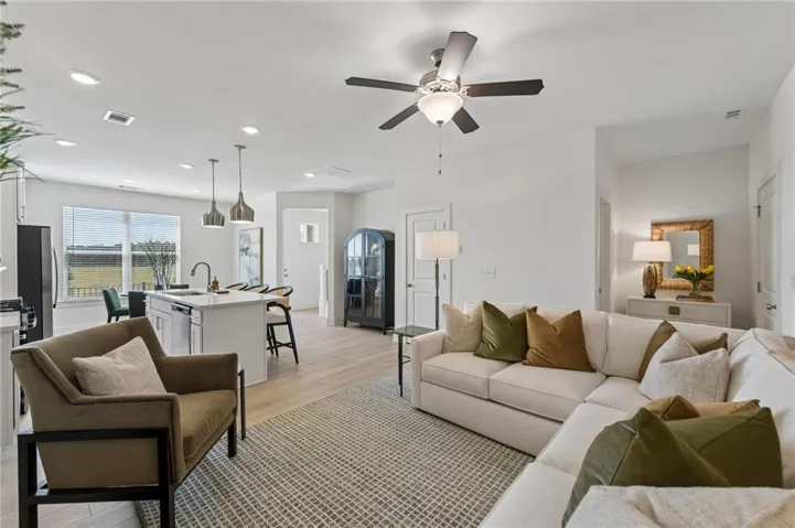 Open-concept living area with wood-finish flooring, recessed lighting, and a ceiling fan