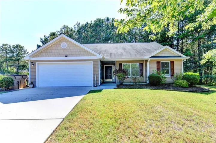Single-story residence featuring a two-car garage, front lawn, and mature landscaping