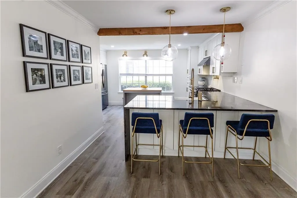 Kitchen with dark hardwood / wood-style flooring, a kitchen bar, kitchen peninsula, stainless steel appliances, and white cabinetry