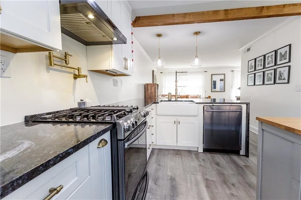 Kitchen with light hardwood / wood-style floors, extractor fan, stainless steel appliances, dark stone countertops, and white cabinets