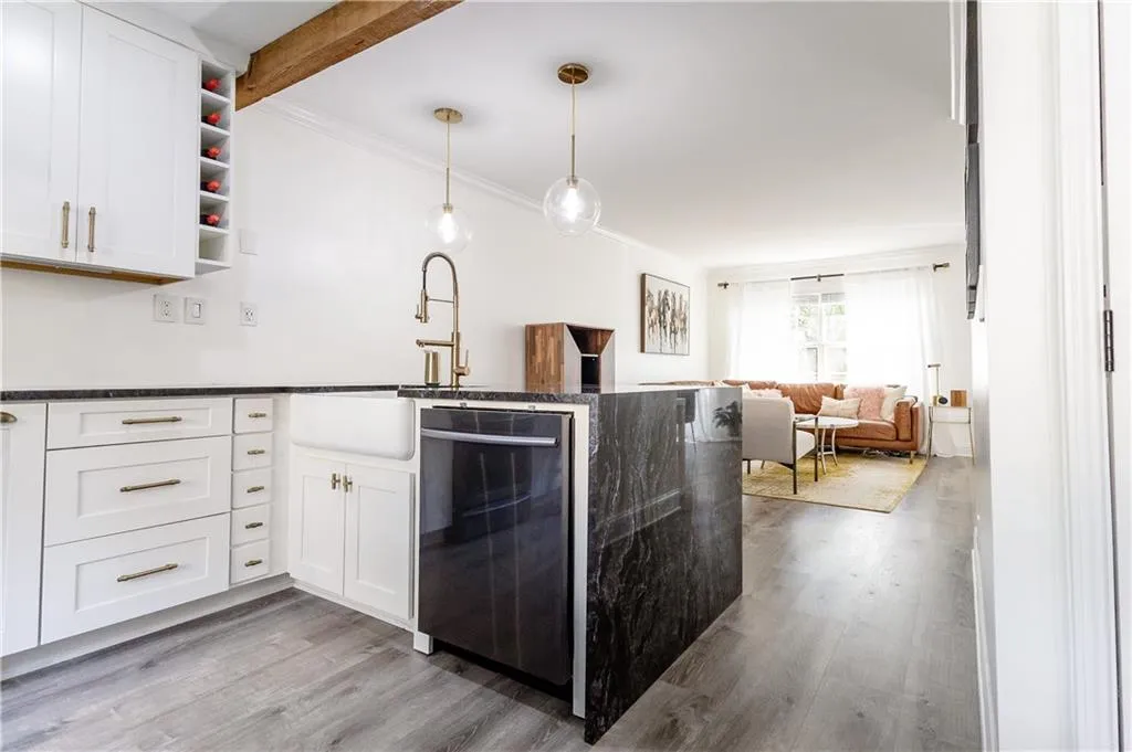 Kitchen with dishwasher, hanging light fixtures, wood-type flooring, and white cabinetry