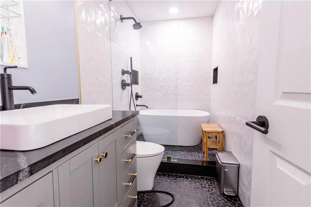 Full bathroom featuring vanity, separate shower and tub, and toilet