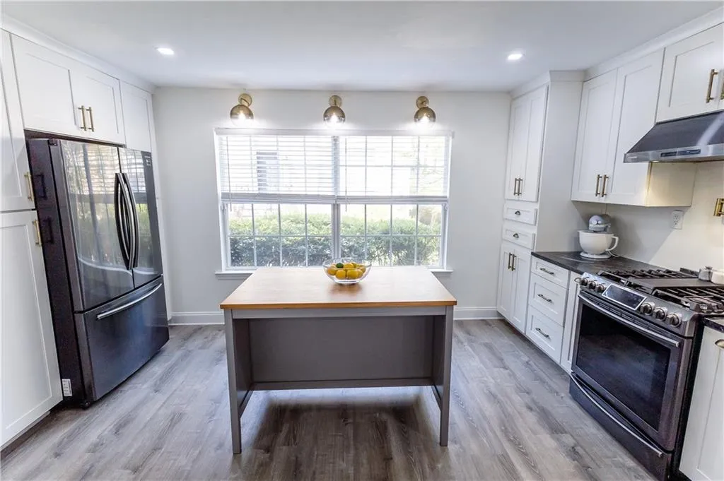 Kitchen with white cabinets, wood counters, light wood-type flooring, stainless steel appliances, and a kitchen island