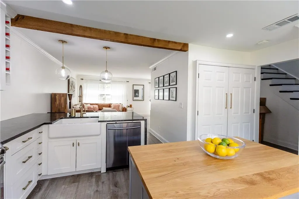 Kitchen featuring dark hardwood / wood-style floors, crown molding, stainless steel dishwasher, sink, and white cabinetry