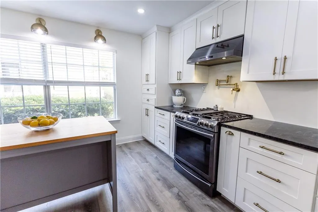 Kitchen featuring gas range oven, hardwood / wood-style flooring, and white cabinets