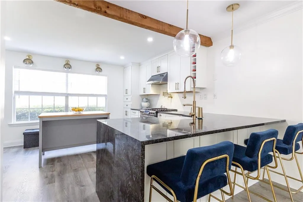 Kitchen featuring dark stone countertops, kitchen peninsula, hanging light fixtures, white cabinets, and light hardwood / wood-style floors