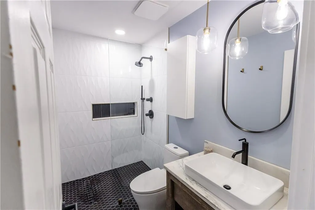 Bathroom with vanity, toilet, and tiled shower