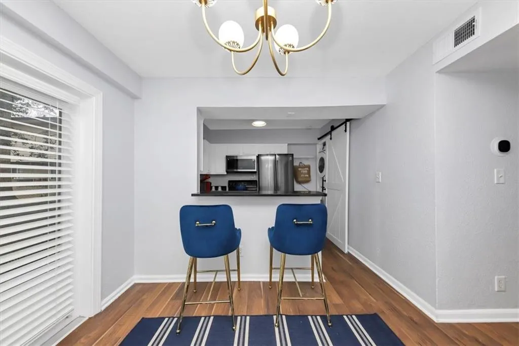 Kitchen with dark hardwood / wood-style floors, kitchen peninsula, a barn door, white cabinets, and appliances with stainless steel finishes