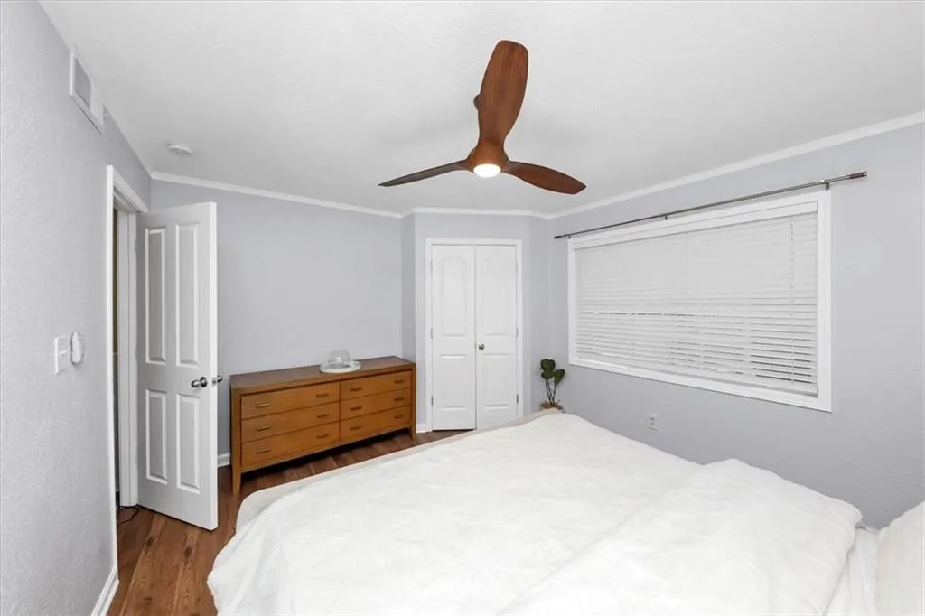 Bedroom featuring hardwood / wood-style flooring, a closet, ornamental molding, and ceiling fan