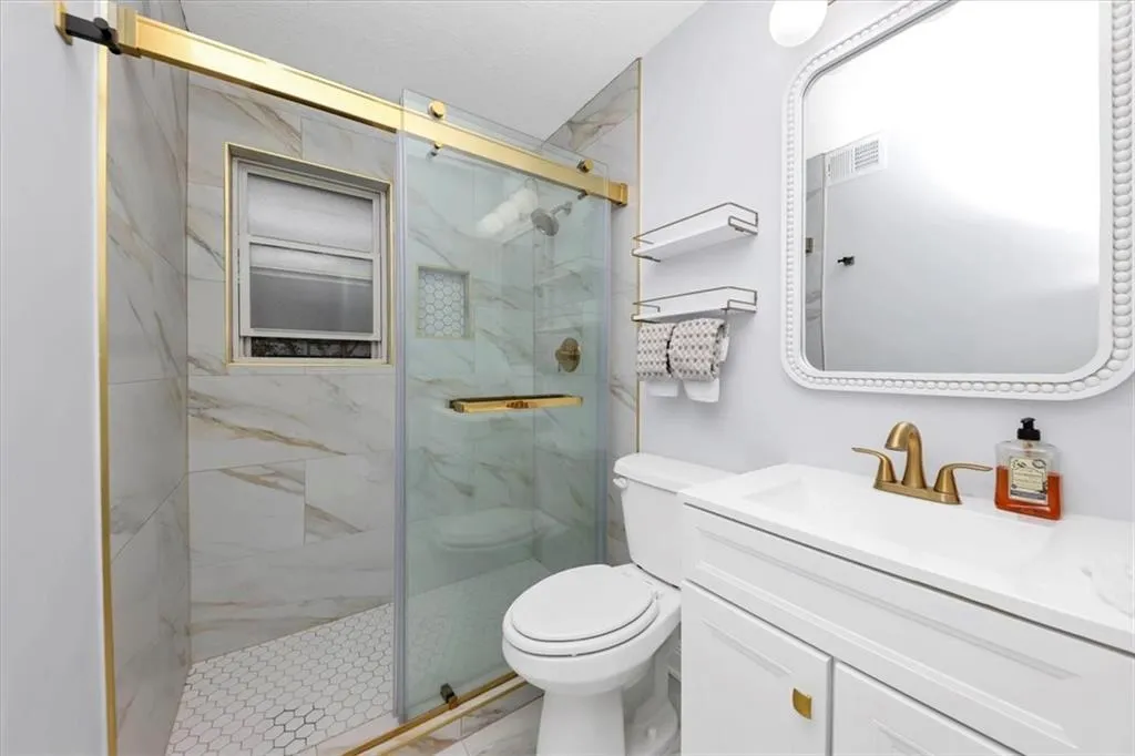 Bathroom with a shower with door, vanity, and toilet