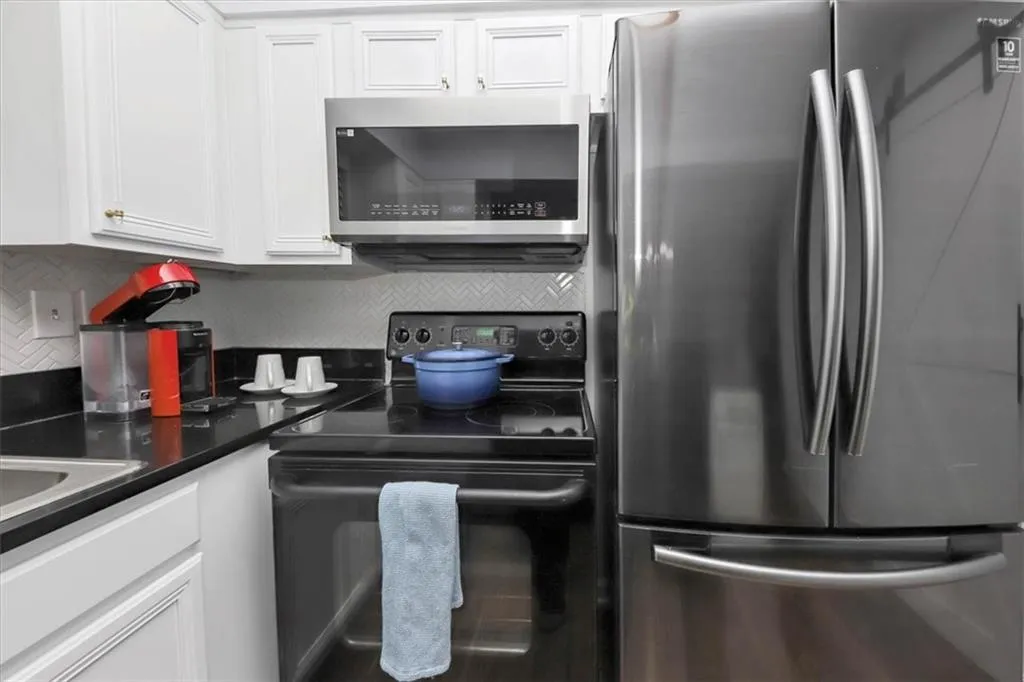 Kitchen with appliances with stainless steel finishes, white cabinetry, and backsplash