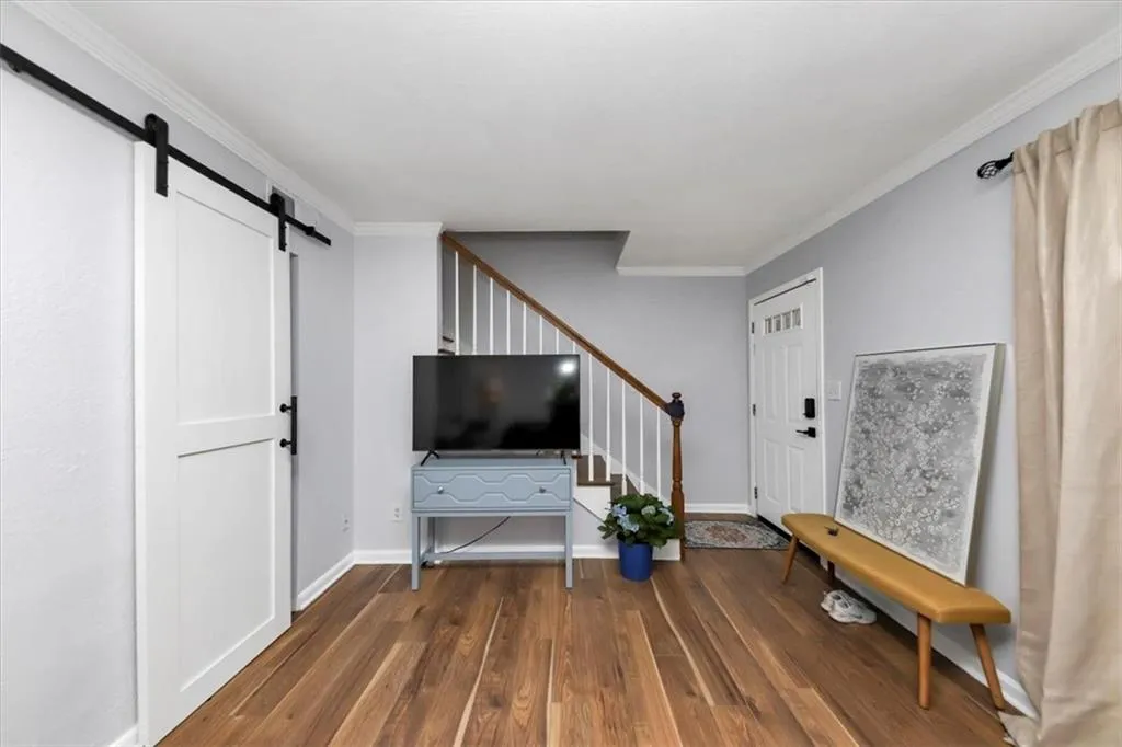Unfurnished room featuring a barn door, hardwood / wood-style flooring, and crown molding