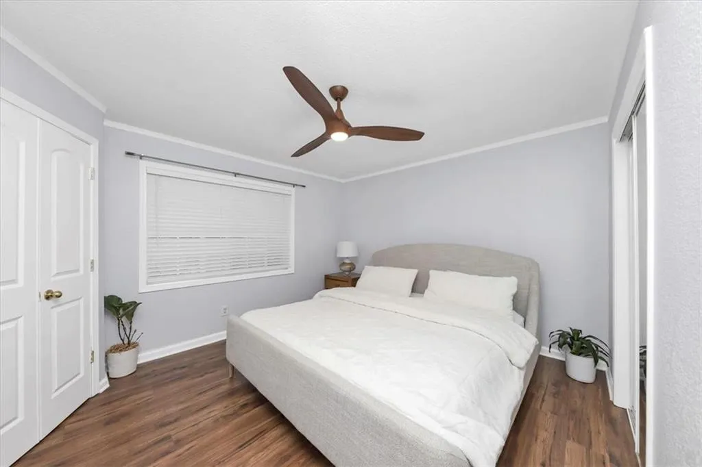 Bedroom featuring crown molding, dark hardwood / wood-style floors, a closet, and ceiling fan