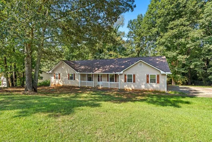 Ranch-style residence featuring a covered front porch with white railings, light-colored siding, and dark shutters