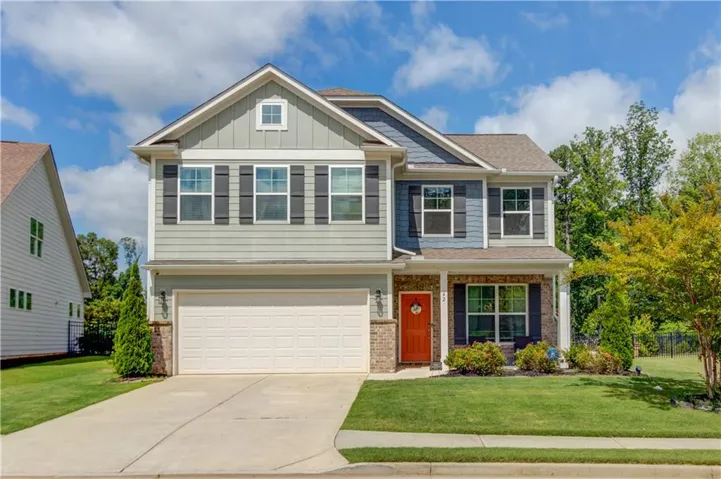 Two-story residence featuring a two-car garage, contrasting siding, and a red entry door