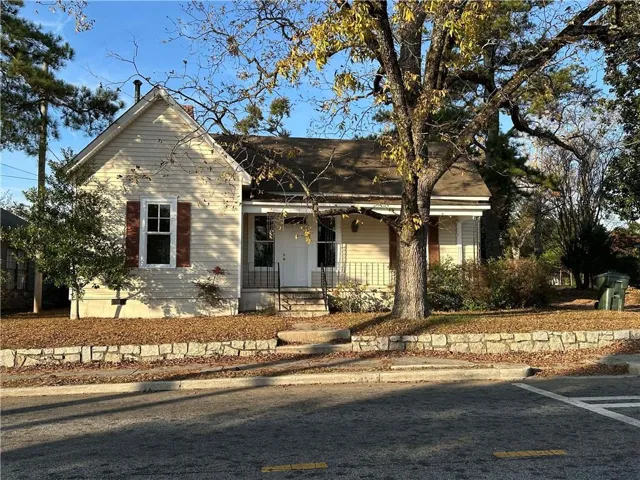 Single-story residence featuring light-colored siding, a covered front porch, and a stone retaining wall