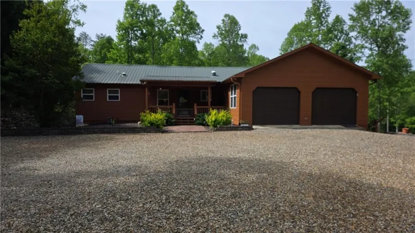 Ranch-style residence featuring a metal roof, wood siding, and a covered front porch