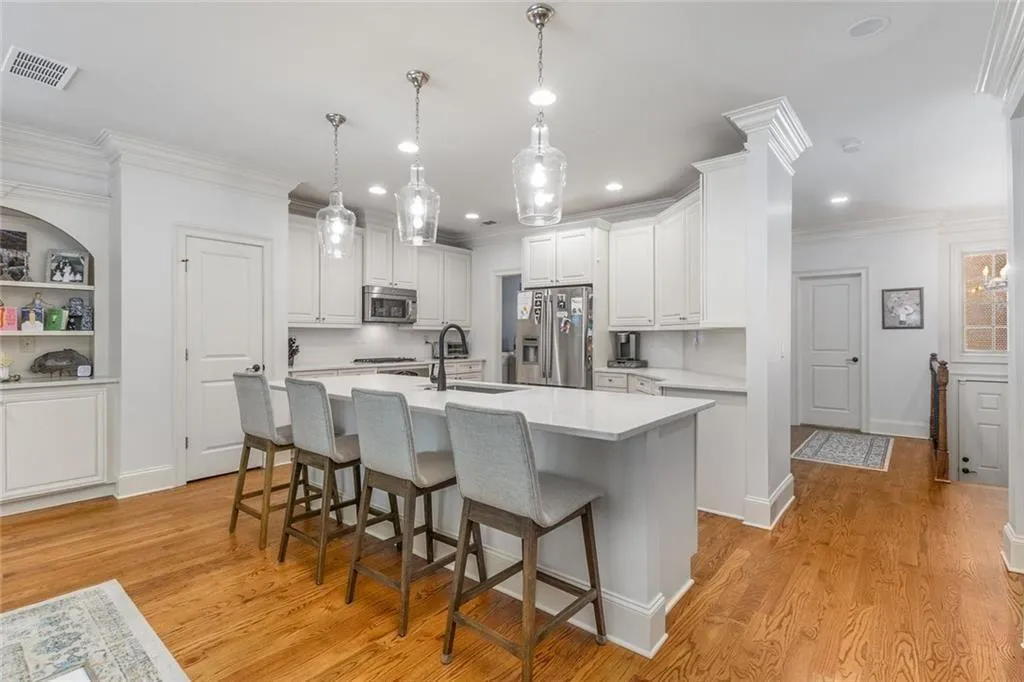 The updated kitchen features white cabinets, quartz countertops, large center island, and stainless steel appliances.