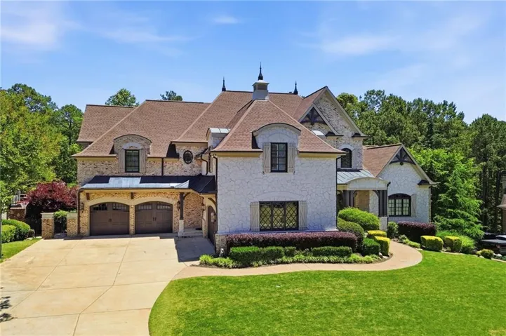 Stately residence featuring a stone and stucco exterior, multiple gables, a covered front entry, and an attached two-car garage