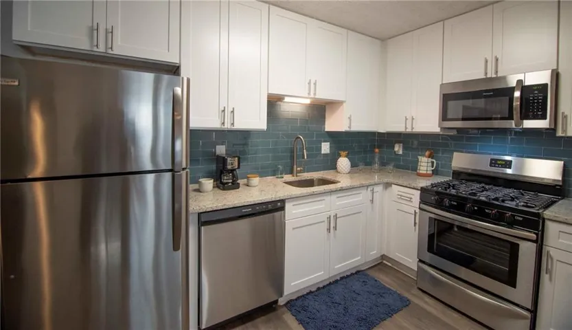 Kitchen with white cabinetry, stainless steel appliances, and sink