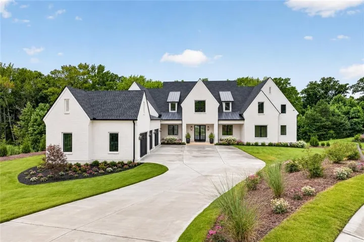 White brick exterior with a dark shingle roof and multiple gables