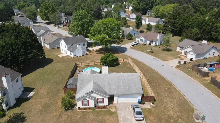 Single-story home featuring a gray shingle roof, attached two-car garage, and a fenced backyard with an above-ground pool