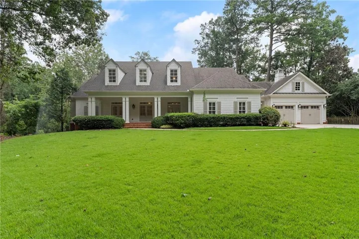 Traditional-style residence featuring a prominent front porch with columns, a dark shingle roof, and three dormer windows