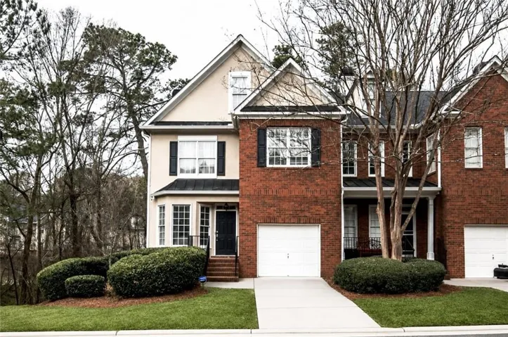 Mixed material facade featuring brick and stucco, prominent bay window, two-car garage with separate doors, black shutters, and a dark front entry door