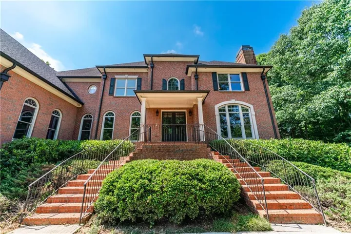 Brick-clad exterior featuring multiple arched windows, dark shutters, and a covered entry