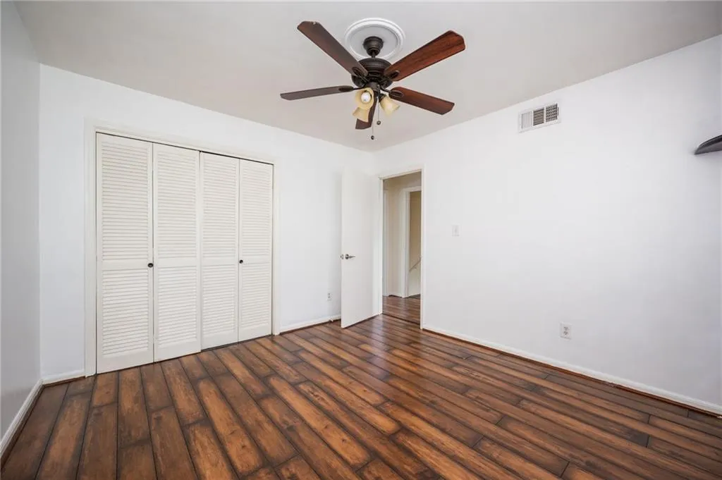 Unfurnished bedroom featuring wood finished floors, a closet, and ceiling fan