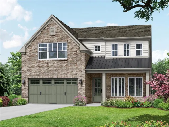 Brick Colonial two-story home featuring a prominent front-gable design with multi-pane windows, attached two-car garage with paneled doors, and manicured landscaping including mature trees and flowering shrubs