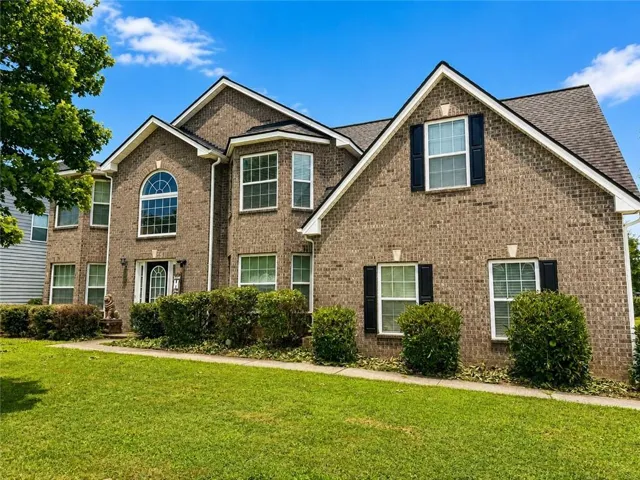 Brick exterior with dark shutters, white window frames, and a prominent arched window
