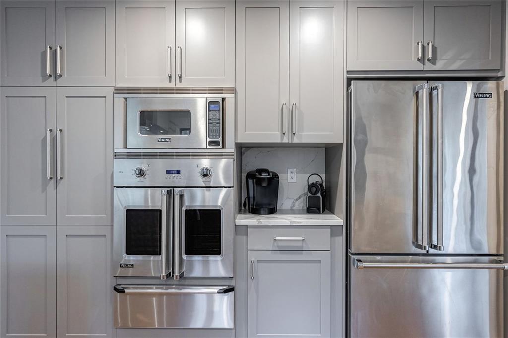 Kitchen with stainless steel appliances, gray cabinetry, and tasteful backsplash