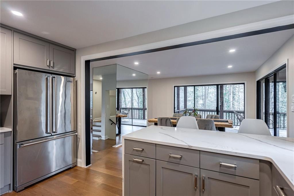 Kitchen featuring light hardwood / wood-style flooring, gray cabinetry, high quality fridge, and light stone counters