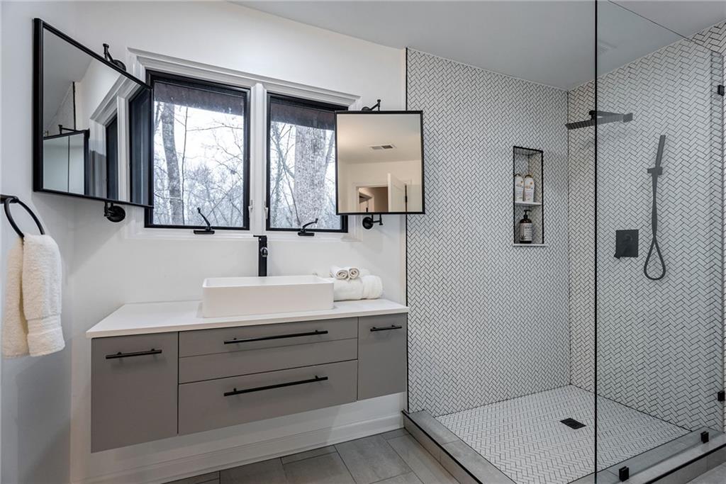 Bathroom with tile floors, a shower with shower door, and vanity with extensive cabinet space