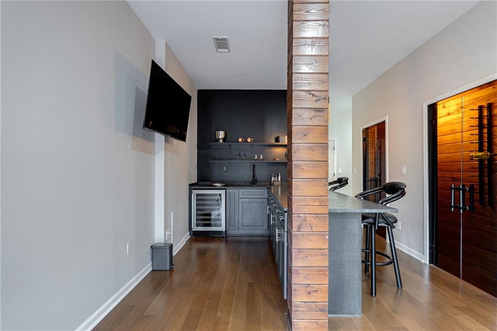 Bar featuring dark hardwood / wood-style floors, wine cooler, and light stone counters