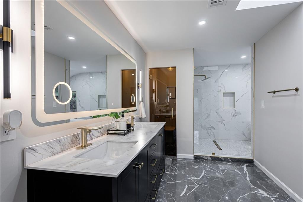 Bathroom with dual bowl vanity, tile floors, and a tile shower