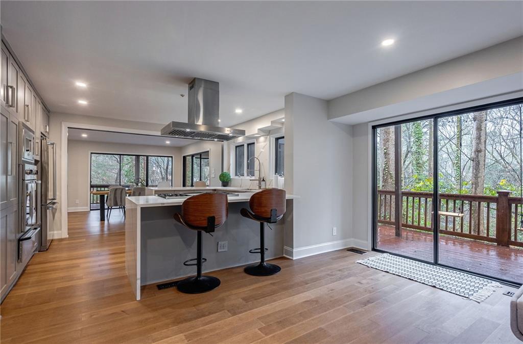 Kitchen featuring a kitchen bar, a wealth of natural light, island exhaust hood, and light wood-type flooring