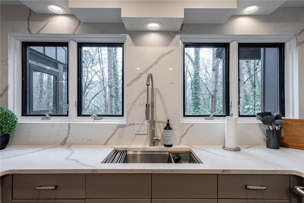 Kitchen featuring light stone countertops, gray cabinets, and sink