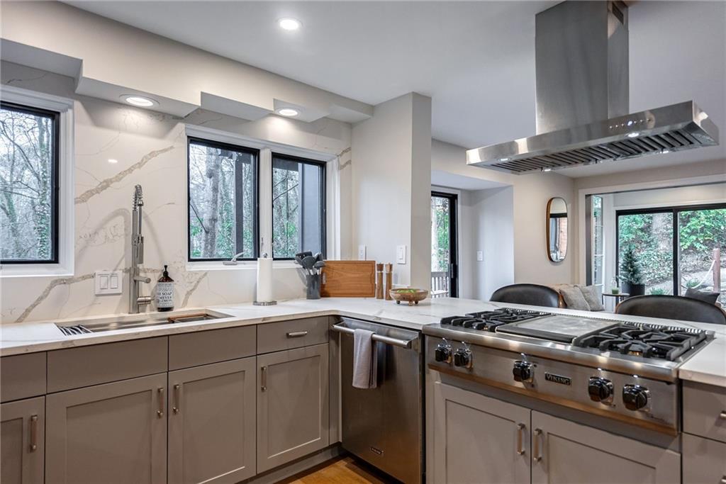 Kitchen with range hood, sink, gray cabinets, and a healthy amount of sunlight