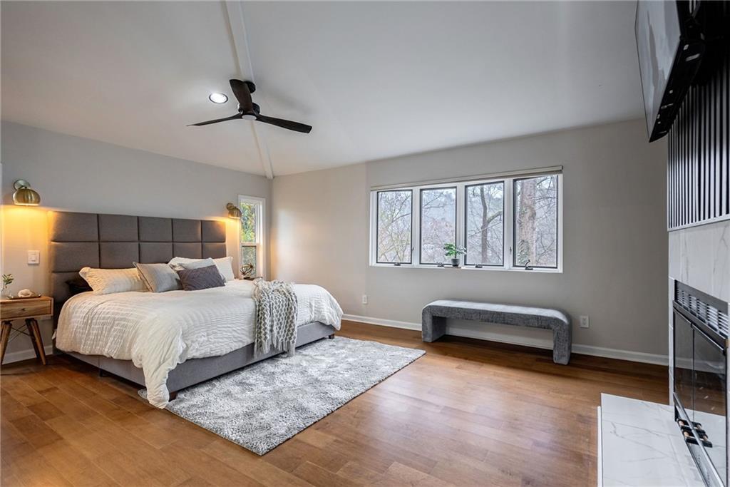 Bedroom with light hardwood / wood-style floors, ceiling fan, and lofted ceiling