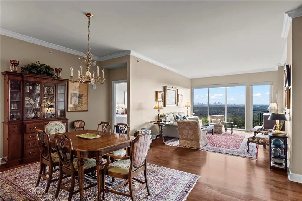 Hardwood-finish flooring, crown molding, a built-in display cabinet, and full-height windows with a cityscape backdrop