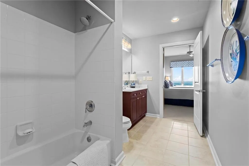 Bathroom featuring a tub/shower combination, single vanity with a solid surface countertop, and tiled flooring