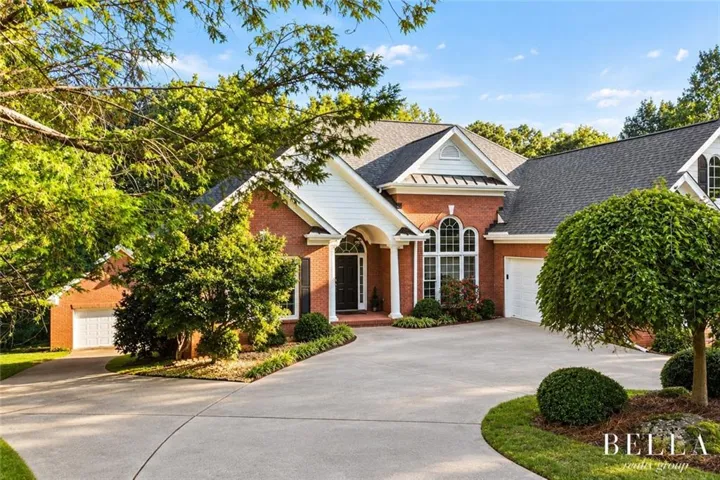 Brick exterior with white trim, arched windows, covered entry, and an attached two-car garage