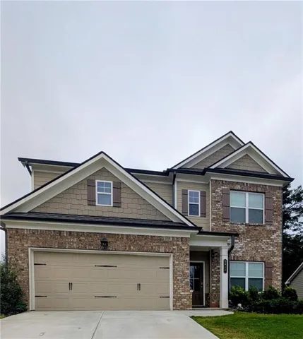 Two-story residence featuring a brick and siding facade, a two-car garage, and multiple gabled rooflines