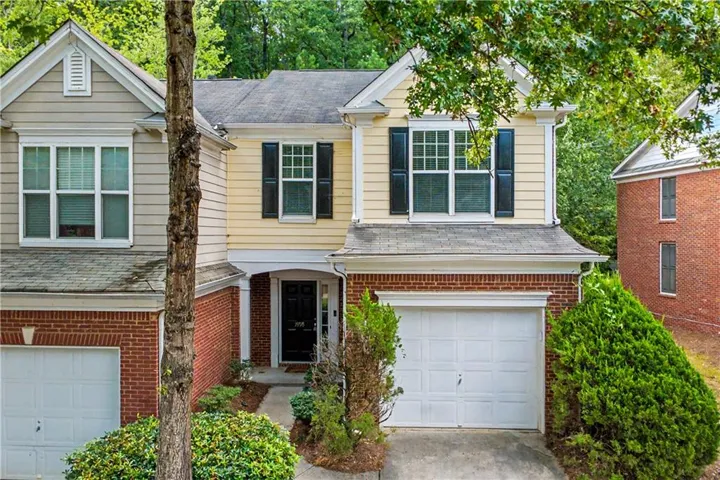 Two-story exterior featuring a brick facade, siding, a front entry, and an attached garage
