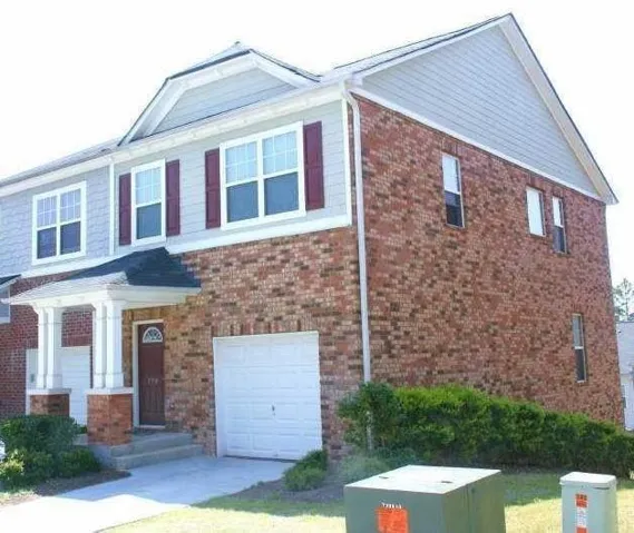 View of front of property featuring a garage, concrete driveway, and brick siding