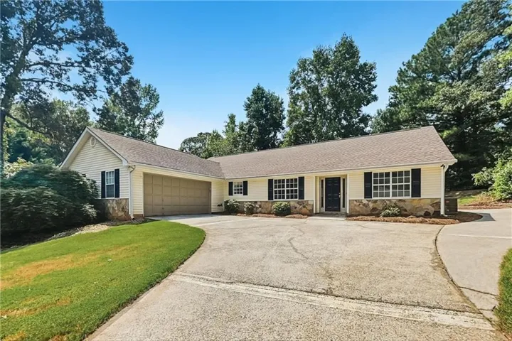 Siding exterior with stone accents, dark shutters, an attached garage, and a concrete driveway