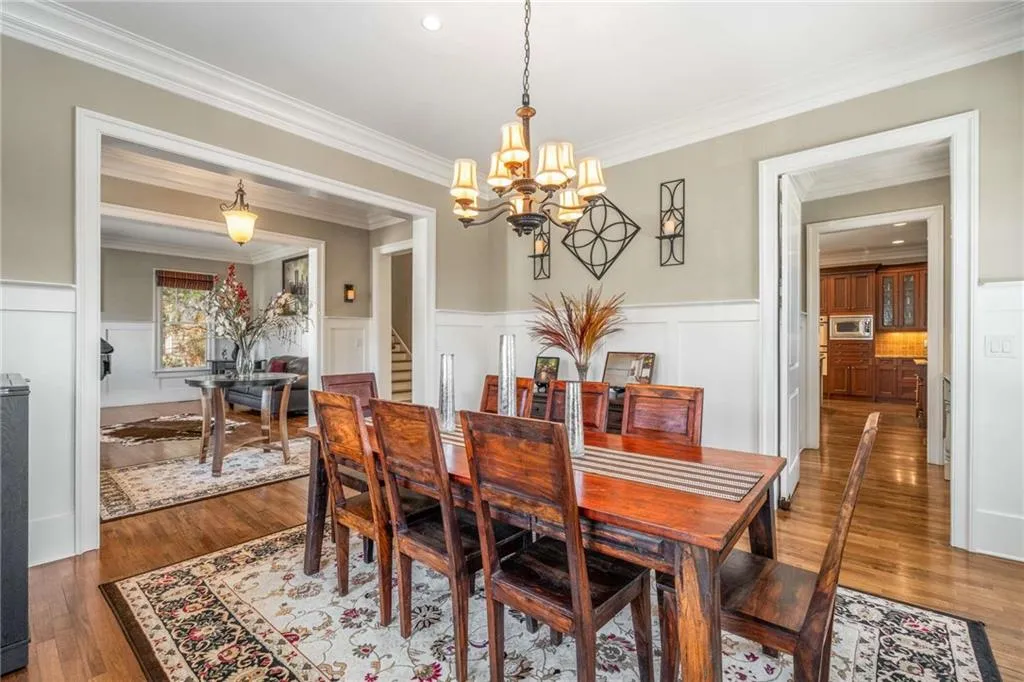Dining space featuring ornamental molding, wainscoting, a notable chandelier, and wood finished floors