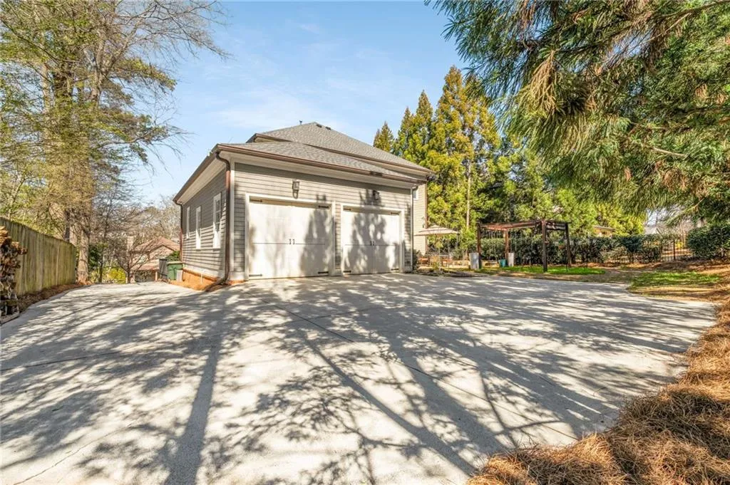 View of property exterior featuring a garage, fence, a pergola, and roof with shingles